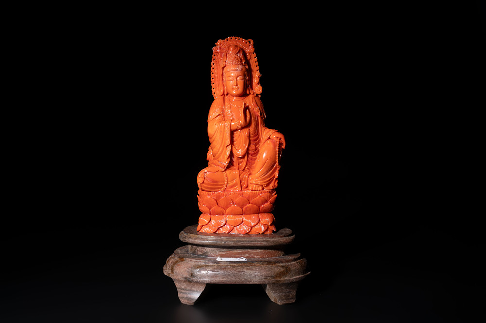 A fine Chinese red coral sculpture of Guanyin seated on a lotus throne on a wooden stand, 19/20th C.