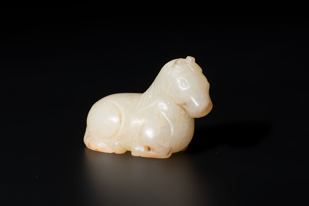 A Chinese white and russet jade pendant in the form of a horse, Song/Ming