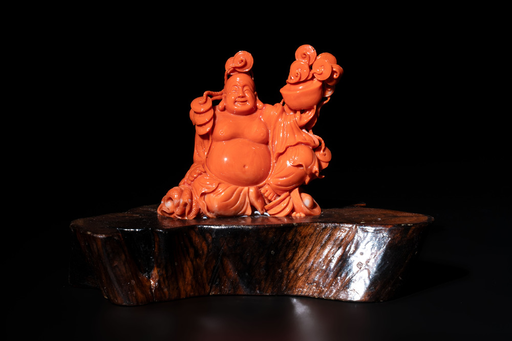 A Chinese red coral sculpture of a Milefo Buddha on wooden stand, 19/20th C.
