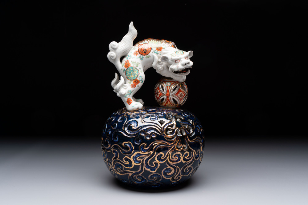 A Japanese Kutani group of a Shishi standing on an openworked brocade ball, 20th C.