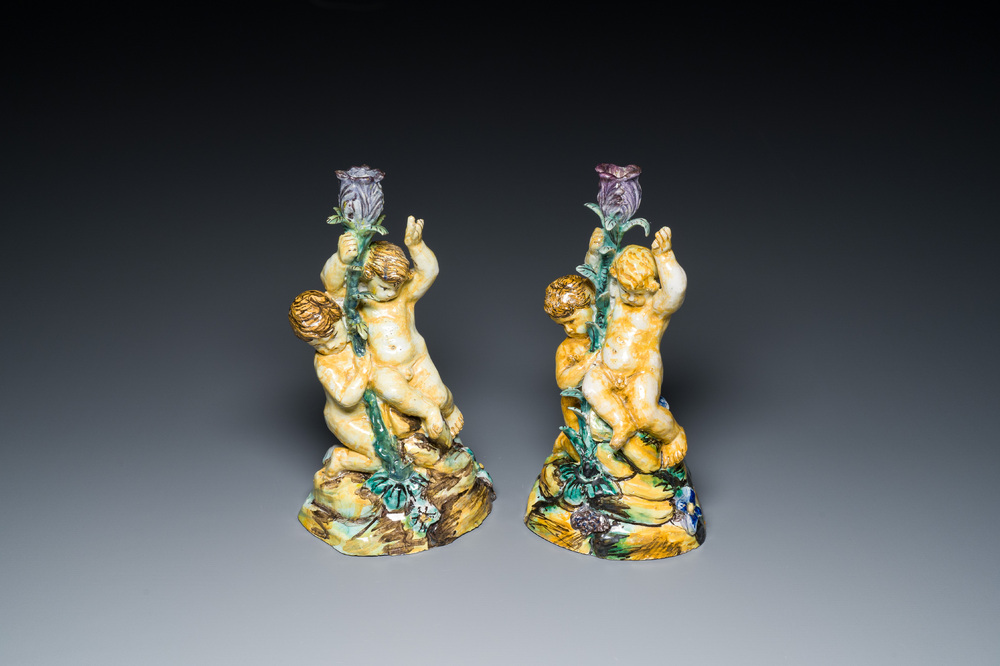 A pair of polychrome Spanish pottery candlesticks with putti on a branch, Talavera, 18th C.