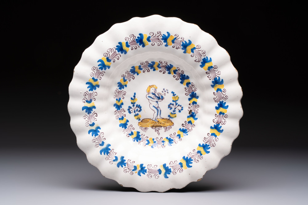 A polychrome lobed Dutch Delftware dish with a putto smoking a pipe, probably Verstraeten workshop, Haarlem, 17th C.