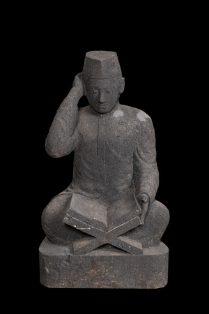 A basalt sculpture of a reading student, Indonesia, 20th C.