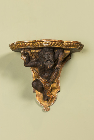 A partly gilt and patinated wooden wall bracket with an atlant, probably Italy, 18/19th C.