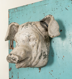 A white-patinated pig's head mounted on a turquoise-ground cabinet door, 20th C.