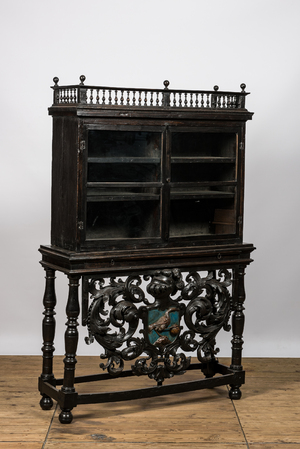 A Spanish ebonised wooden display cabinet on richly carved armorial stand, 19th C.