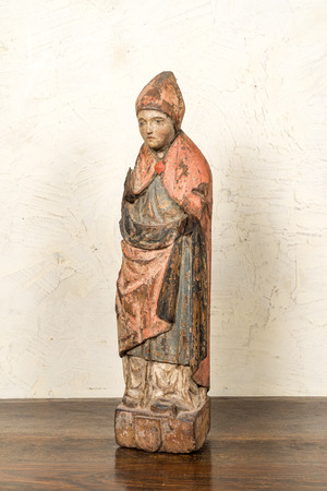 A Flemish carved and polychromed oak figure of a bishop on an armorial base, ca. 1500