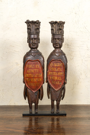 A pair of polychromed wooden reliefs depicting atlants bearing inscribed shields, 17th C.
