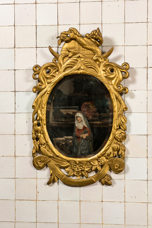 A gilt wooden mirror with floral design and crowned with a snake, 19th C.