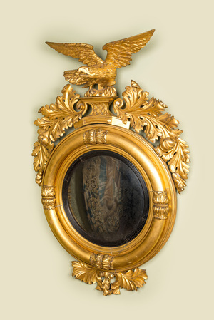 An impressive gilt wooden eagle-topped mirror with ebonised inner medallion, 19th C.