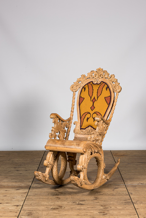 A richly carved wooden rocking chair with snake-shaped legs, 20th C.