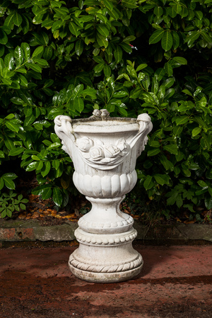 A white painted concrete garden urn on stand, 20th C.