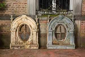 A pair of cast iron 'oeuil-de-boeuf's with a mascaron, 19th C.