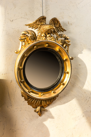 A gilt wooden eagle-topped butler mirror with ebonised border, ca. 1900