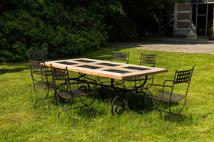 A wrought iron table with slate and wooden top with six chairs, 20th C.
